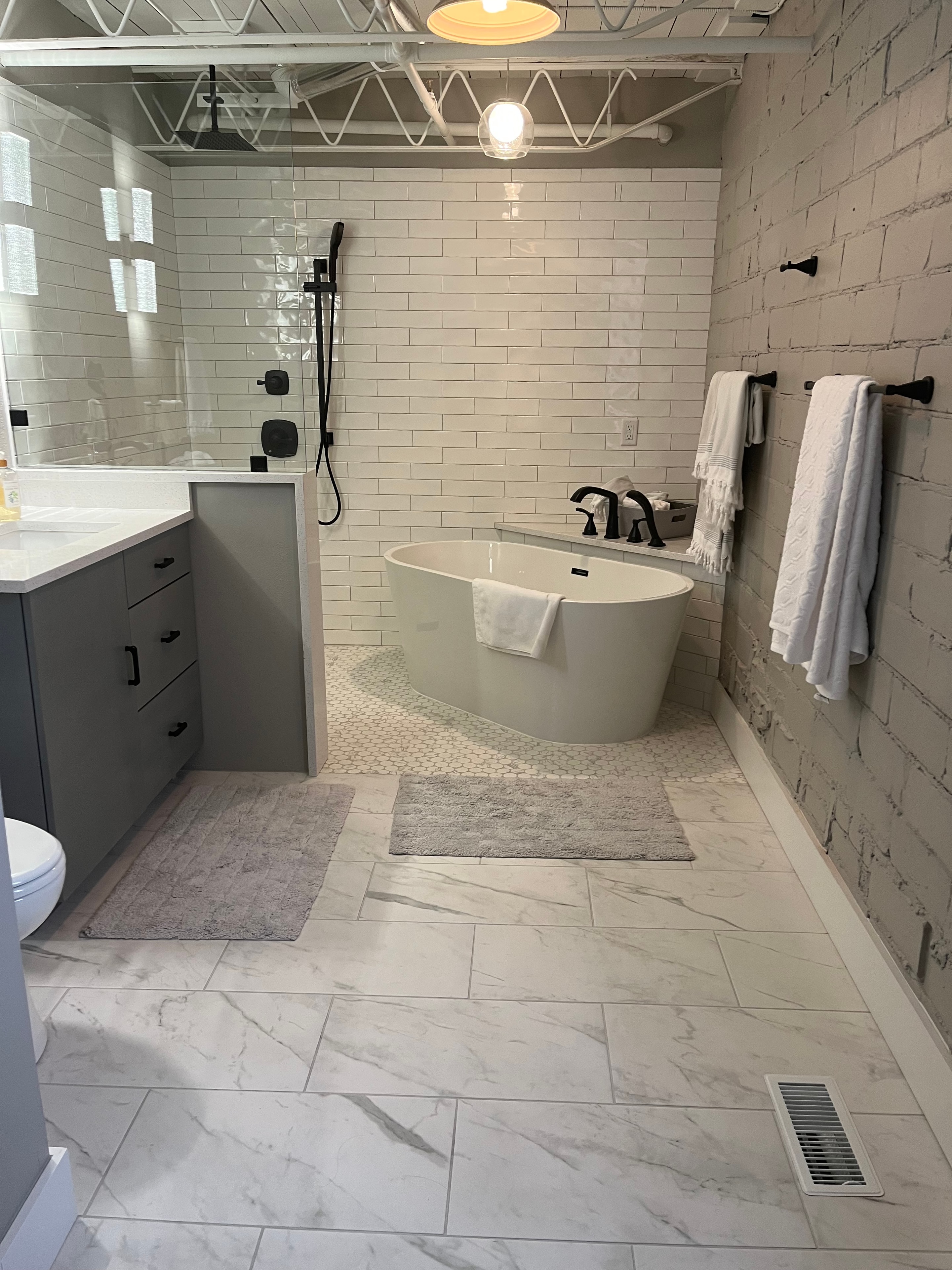 Custom bathroom with white subway tile, clawfoot tub, and penny tile shower floor