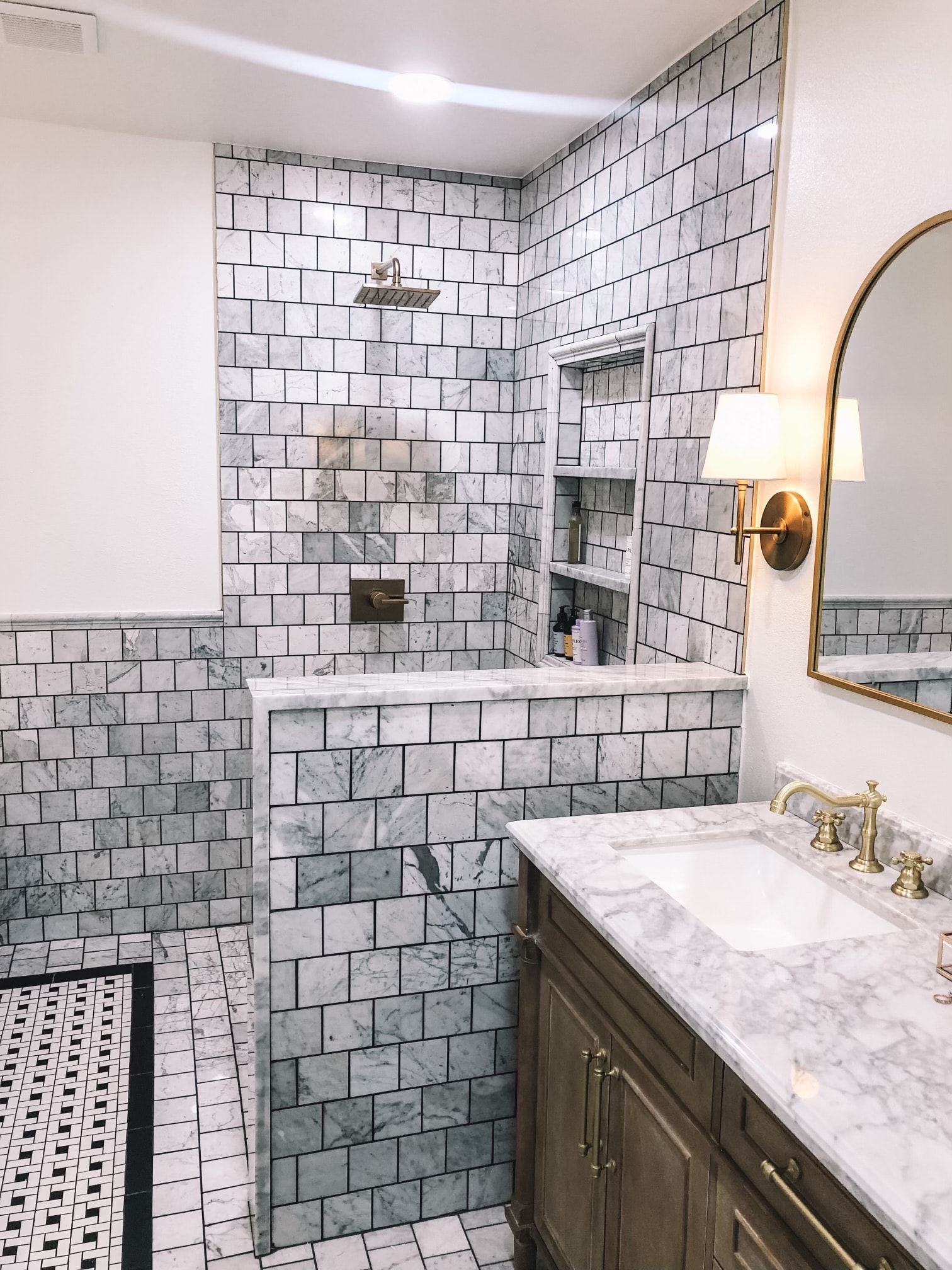 Custom bathroom with gray marble subway tile, brass fixtures, and basket weave floor