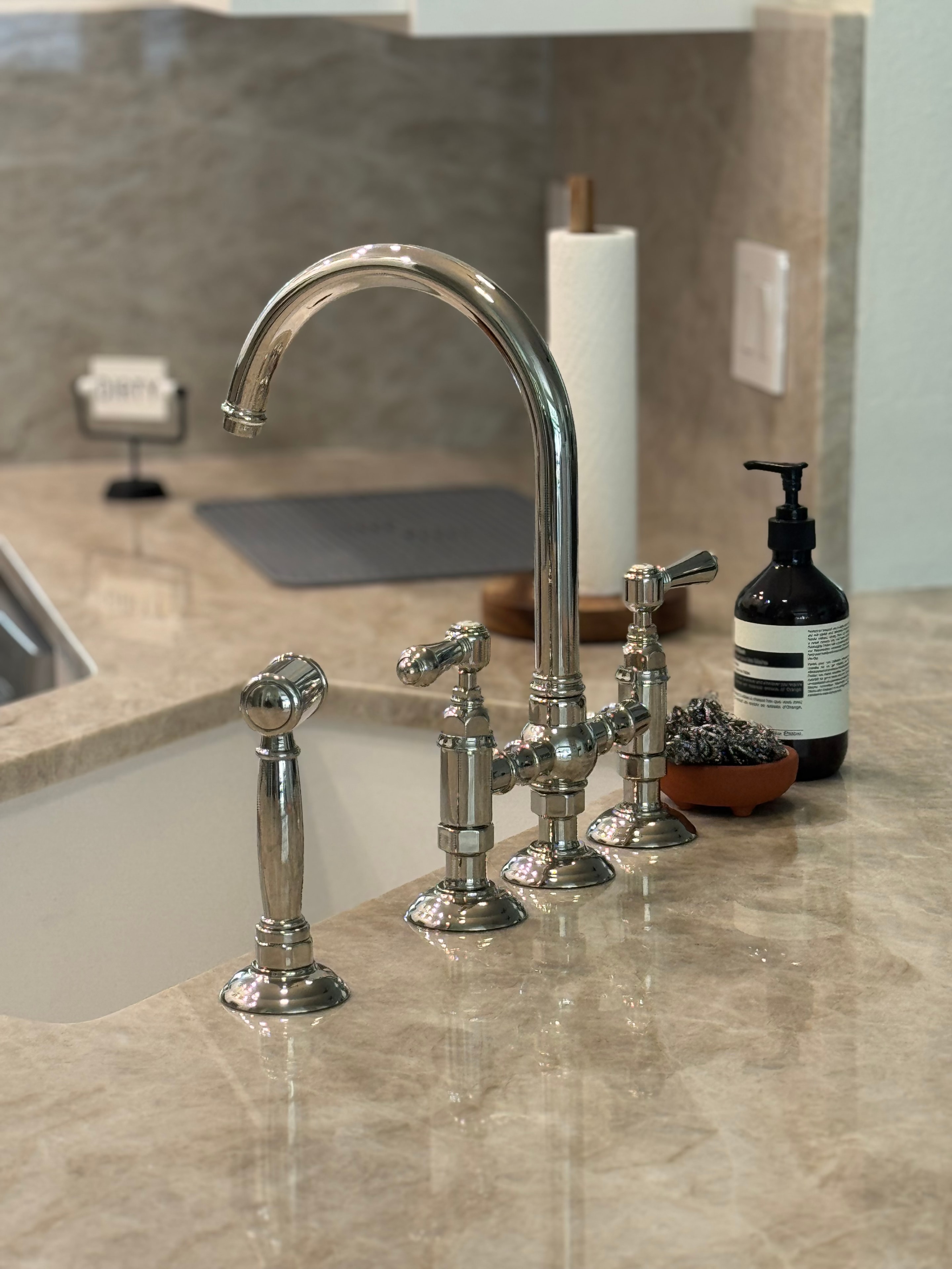 Kitchen renovation detail — bridge faucet on marble countertop by BMW Renovations