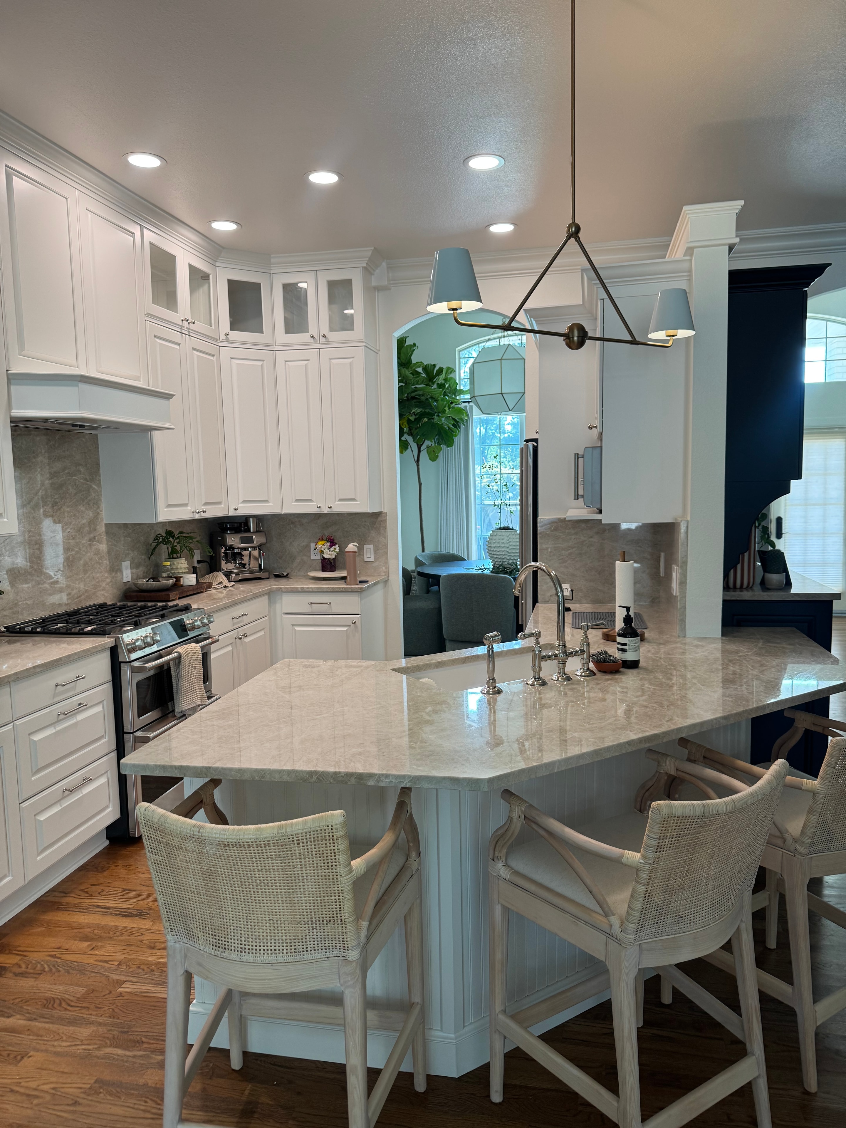 Kitchen remodel with white raised-panel cabinets, large island, and pendant lighting